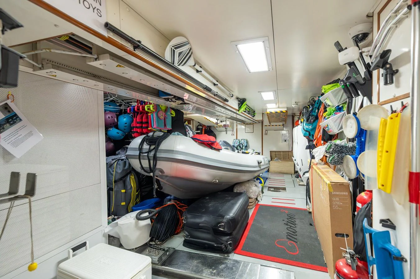 The yacht's toy storage area is well-organized, featuring a variety of equipment and a small inflatable boat. aboard EMOTION 2 Yacht for Sale