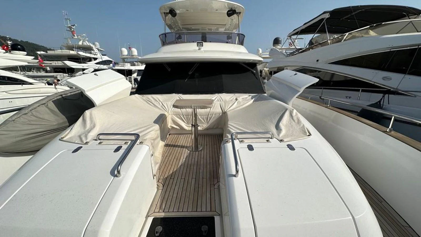 The yacht is docked among other vessels, showcasing its sleek and modern exterior design. aboard NINE NINE WINE Yacht for Sale