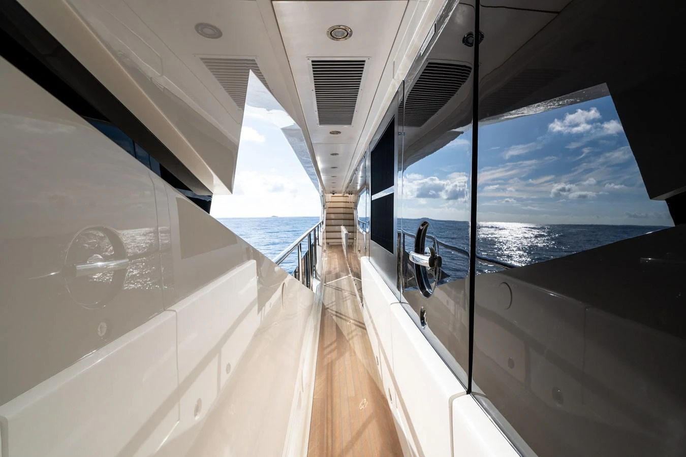 The sleek side deck of the yacht offers a stunning view of the sea under a clear sky. aboard ALADDIN Yacht for Sale