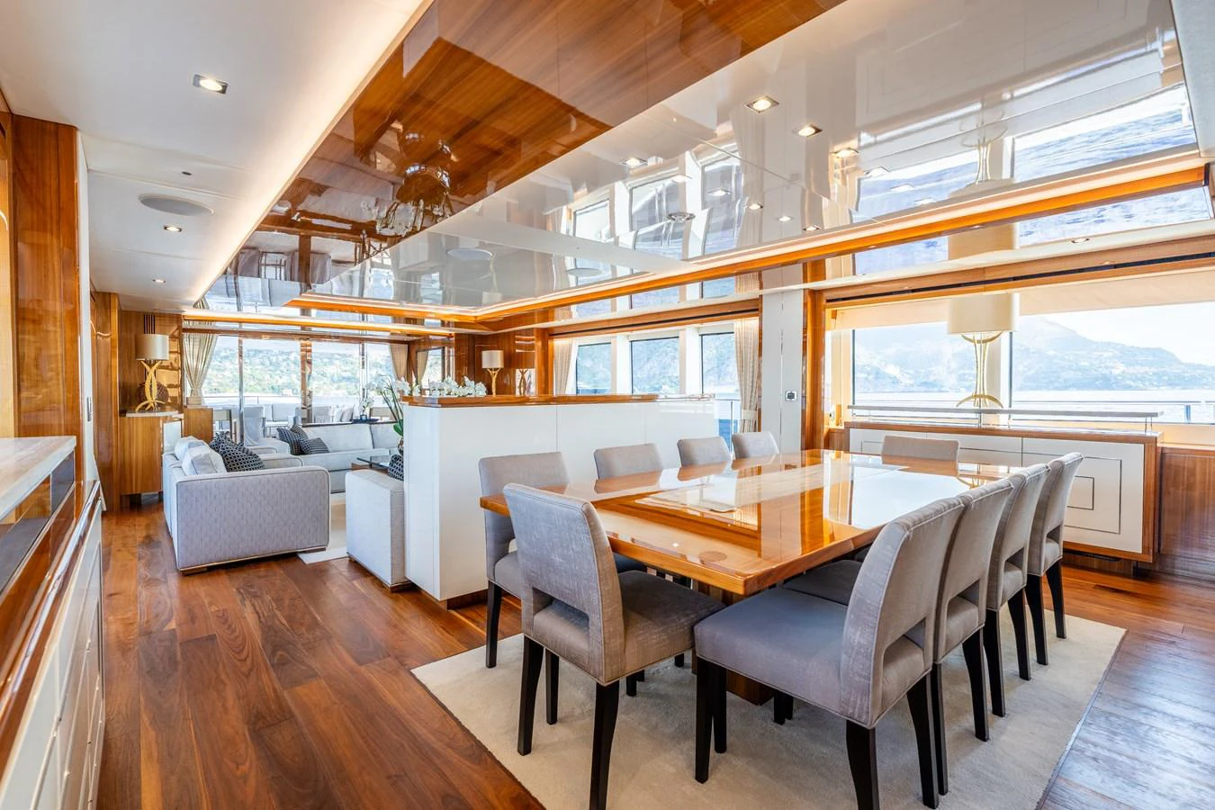 The yacht's dining area features a spacious table with plush seating, surrounded by elegant wood finishes and large windows offering scenic views. aboard ALADDIN Yacht for Sale