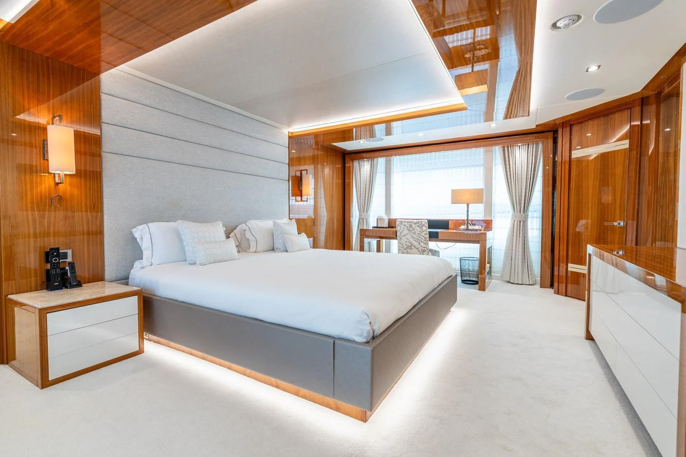 The master stateroom features a luxurious bed, elegant wood finishes, and ample natural light. aboard ALADDIN Yacht for Sale