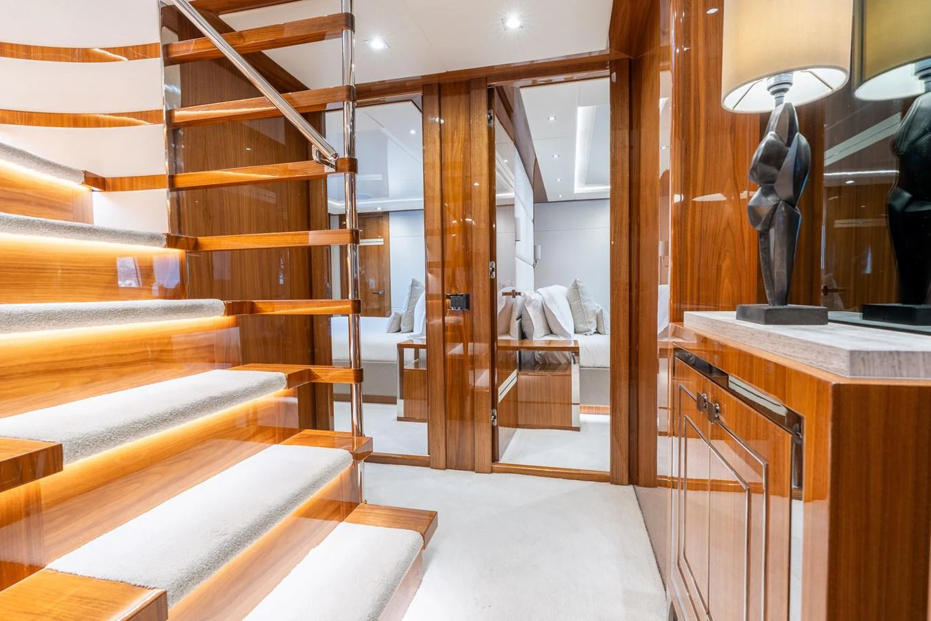 The yacht's interior features a beautifully lit staircase with polished wood and modern decor. aboard ALADDIN Yacht for Sale