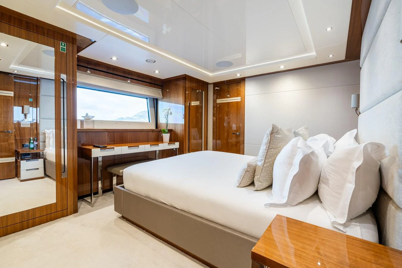 A luxurious stateroom featuring a large bed, elegant wood finishes, and ample natural light. aboard ALADDIN Yacht for Sale