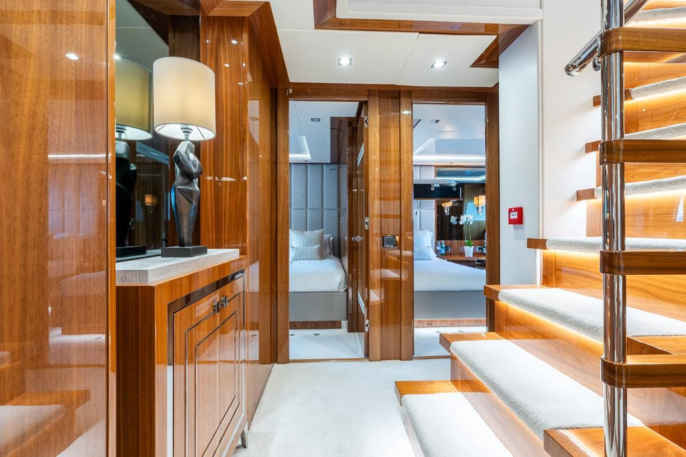 The yacht's interior features a luxurious hallway with polished wood finishes and a staircase leading to the lower deck. aboard ALADDIN Yacht for Sale