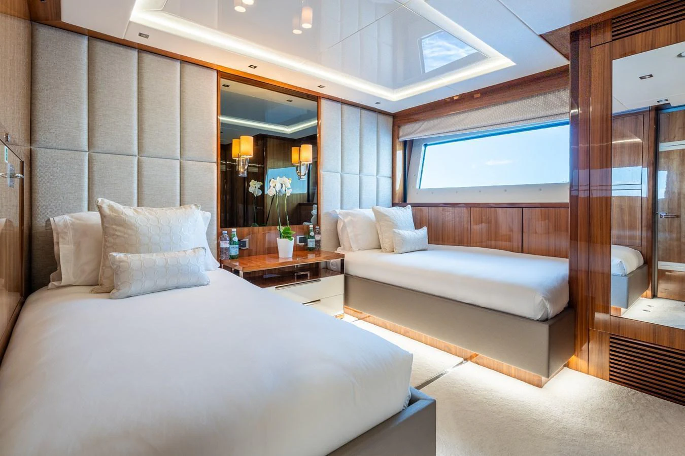 The guest stateroom features twin beds, elegant wood paneling, and a large window for natural light. aboard ALADDIN Yacht for Sale