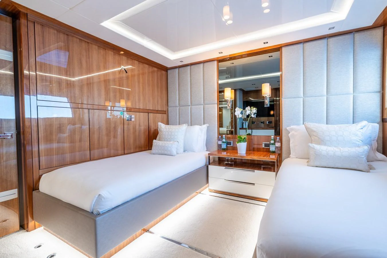 The guest stateroom features twin beds, elegant wood paneling, and soft ambient lighting. aboard ALADDIN Yacht for Sale