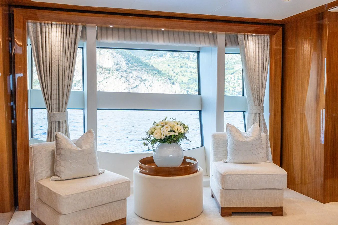 The yacht's interior features a cozy seating area with large windows offering stunning views of the water and surrounding landscape. aboard ALADDIN Yacht for Sale