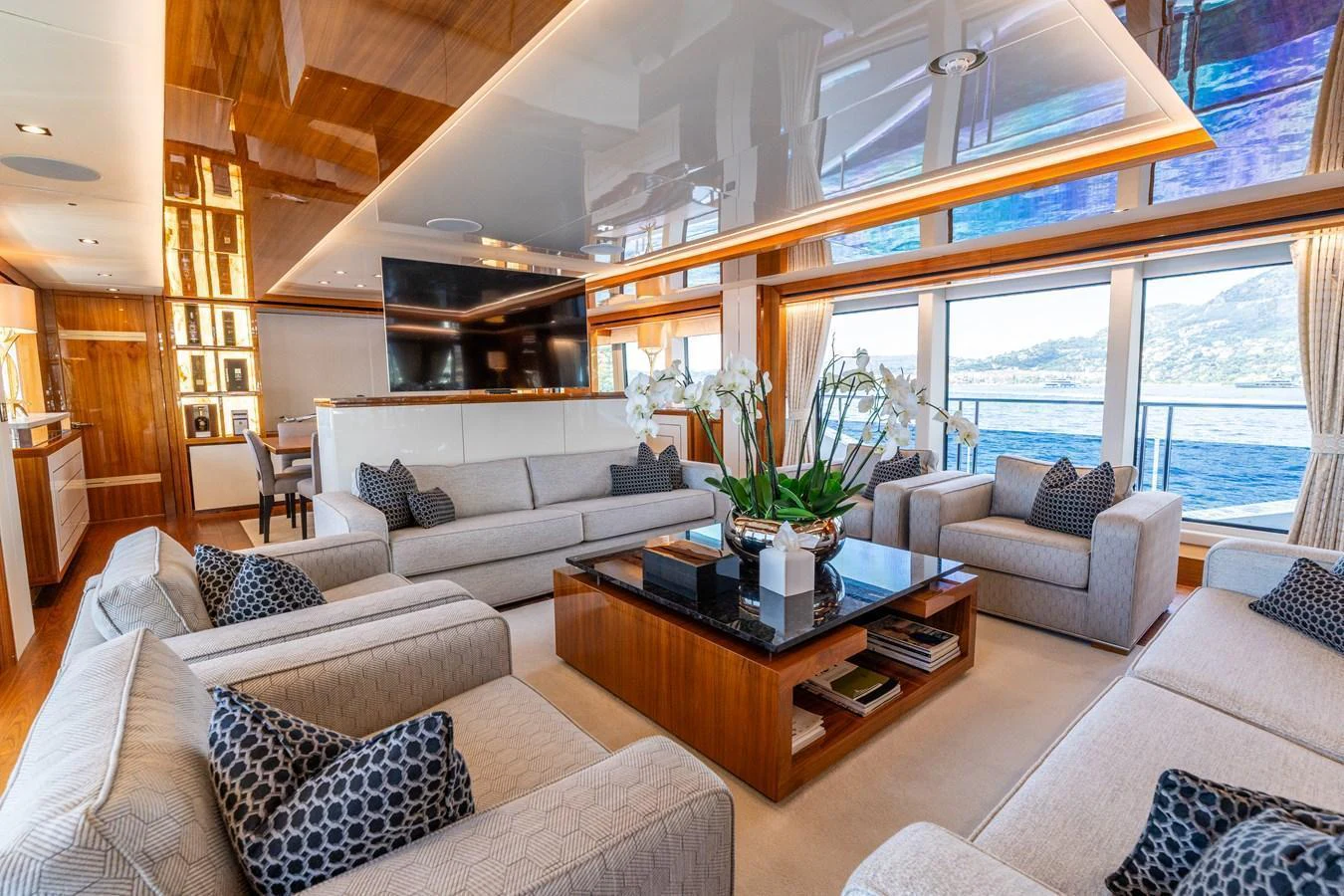 The salon features luxurious seating with elegant decor and expansive windows offering stunning ocean views. aboard ALADDIN Yacht for Sale