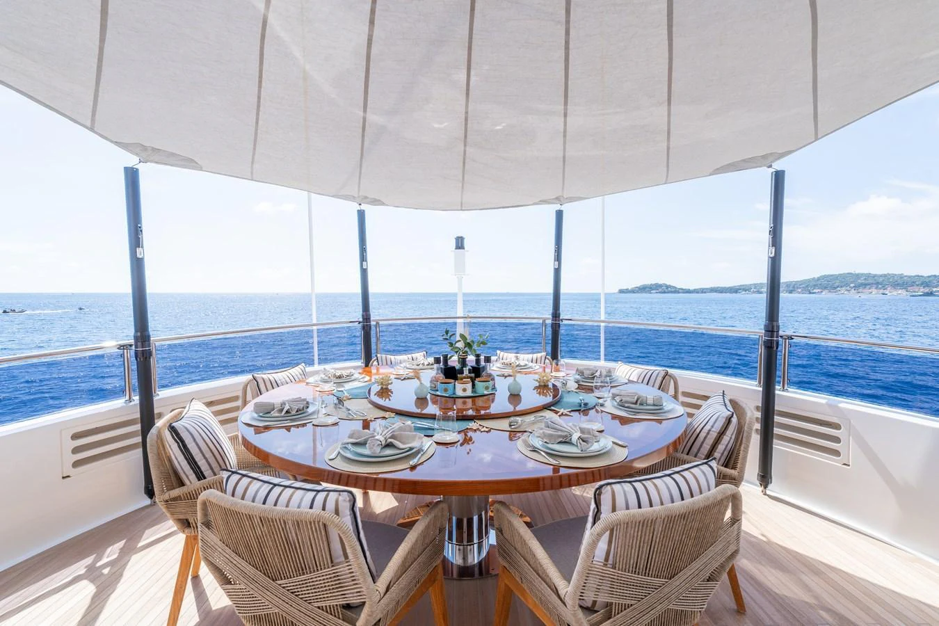 The yacht features an elegant alfresco dining area with a round table set for a meal, offering stunning ocean views. aboard ALADDIN Yacht for Sale