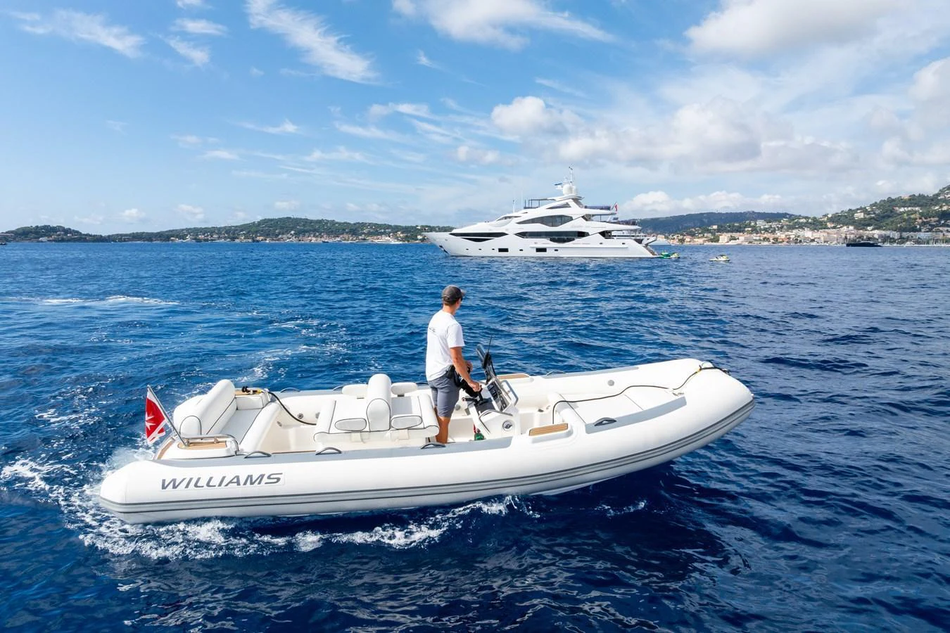 A sleek tender boat glides across the water with a luxurious yacht in the background. aboard ALADDIN Yacht for Sale
