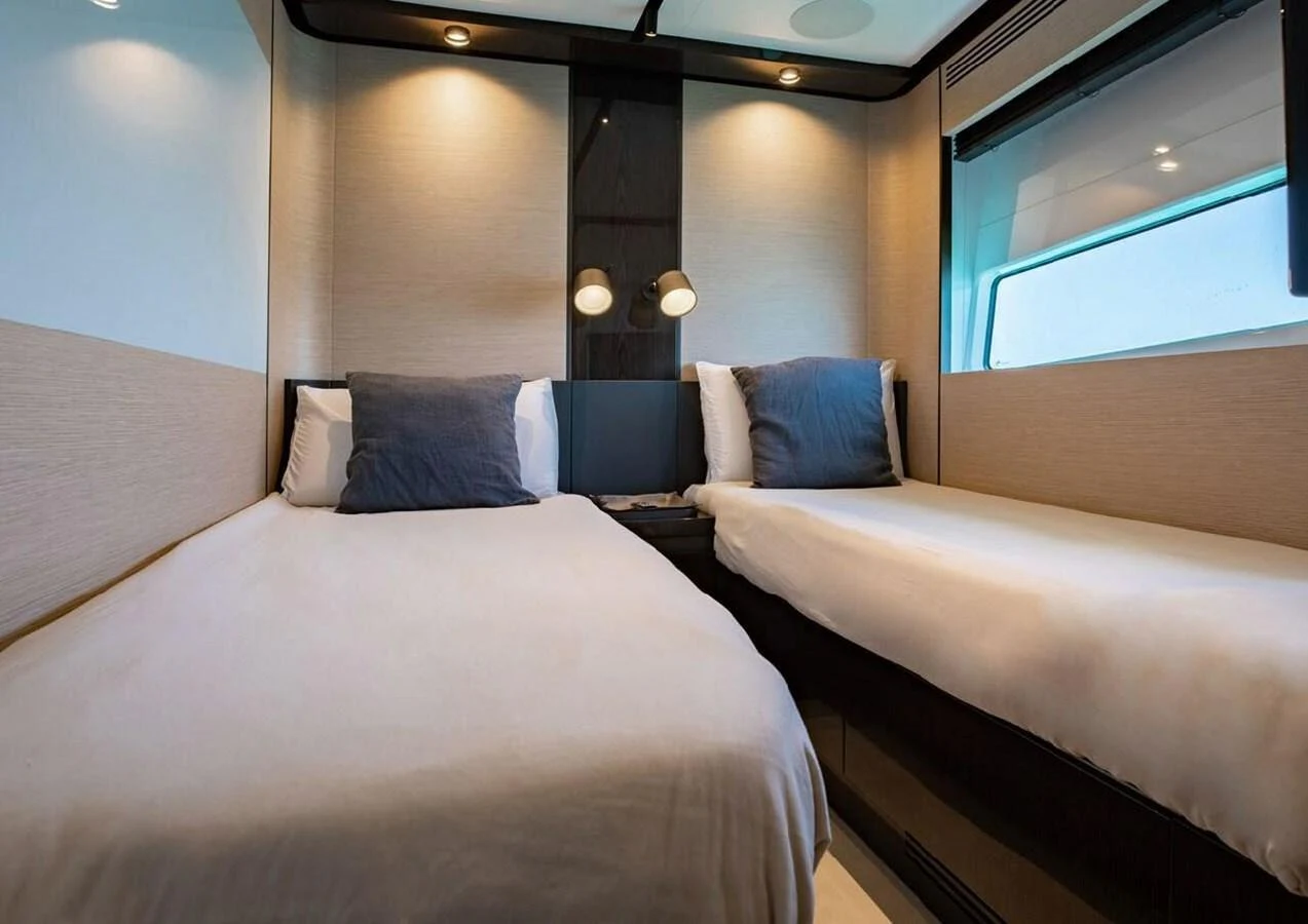 The guest stateroom features two twin beds with modern lighting and a sleek design. aboard LANCE WEST Yacht for Sale