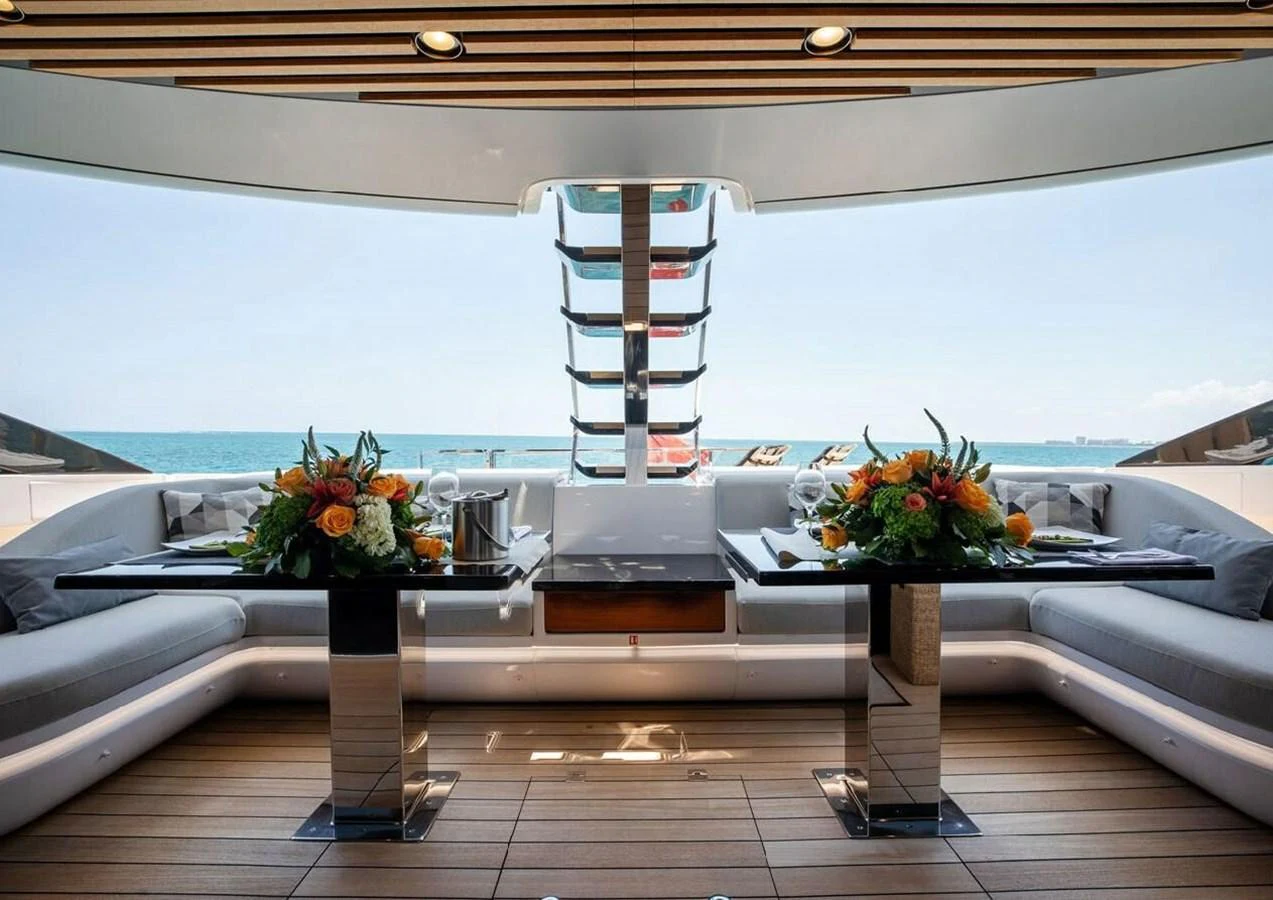 The aft deck features a stylish dining area with elegant floral arrangements and a stunning sea view. aboard LANCE WEST Yacht for Sale