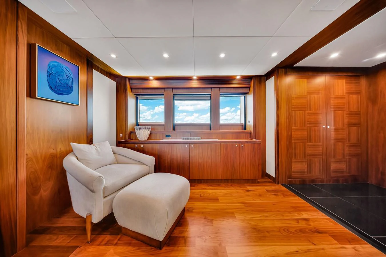 The yacht's interior features a cozy seating area with elegant wood paneling and large windows offering a stunning view. aboard NATURAL 9 Yacht for Sale