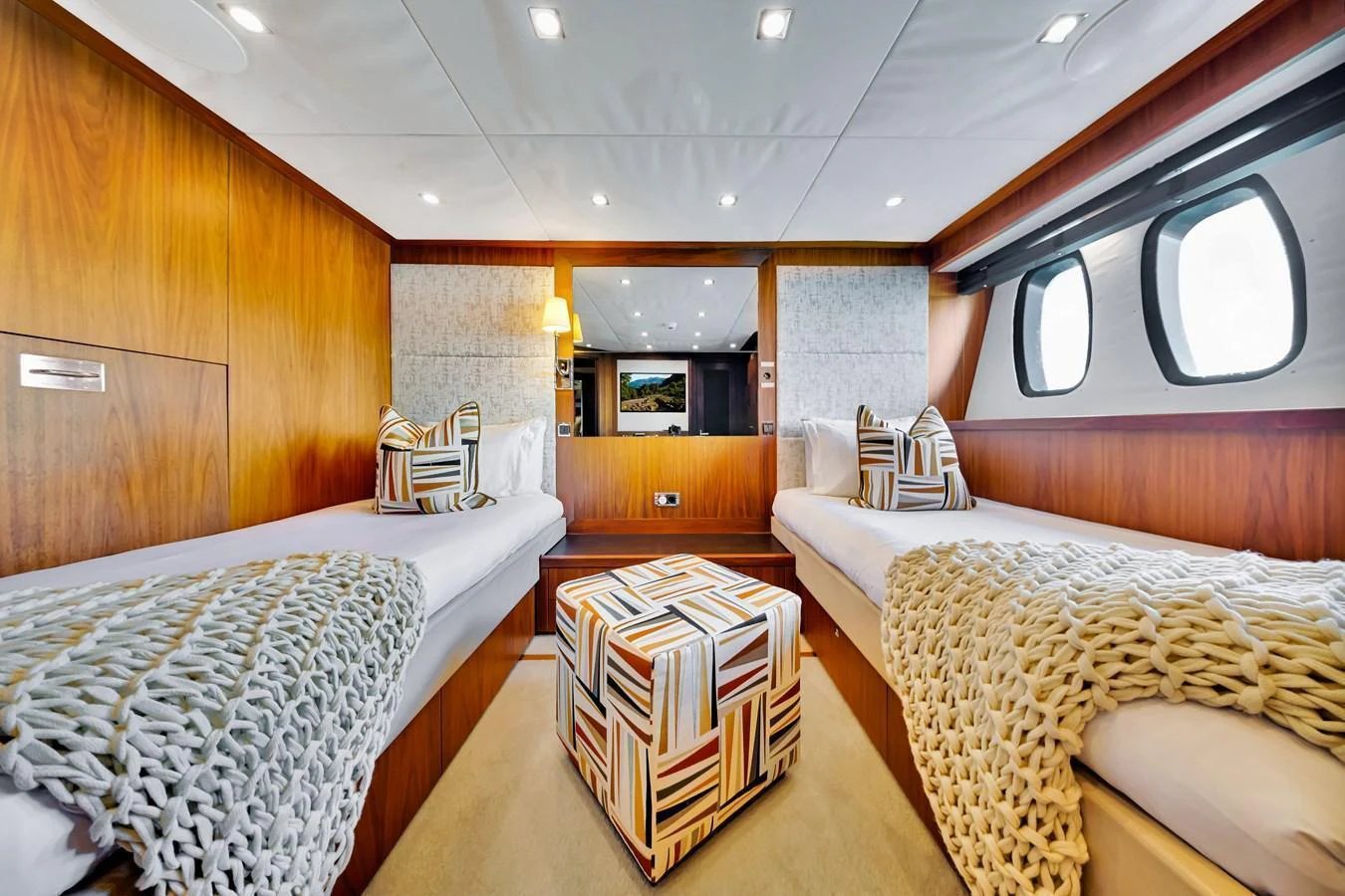 The guest stateroom features twin beds with stylish decor and ample natural light from the portholes. aboard NATURAL 9 Yacht for Sale
