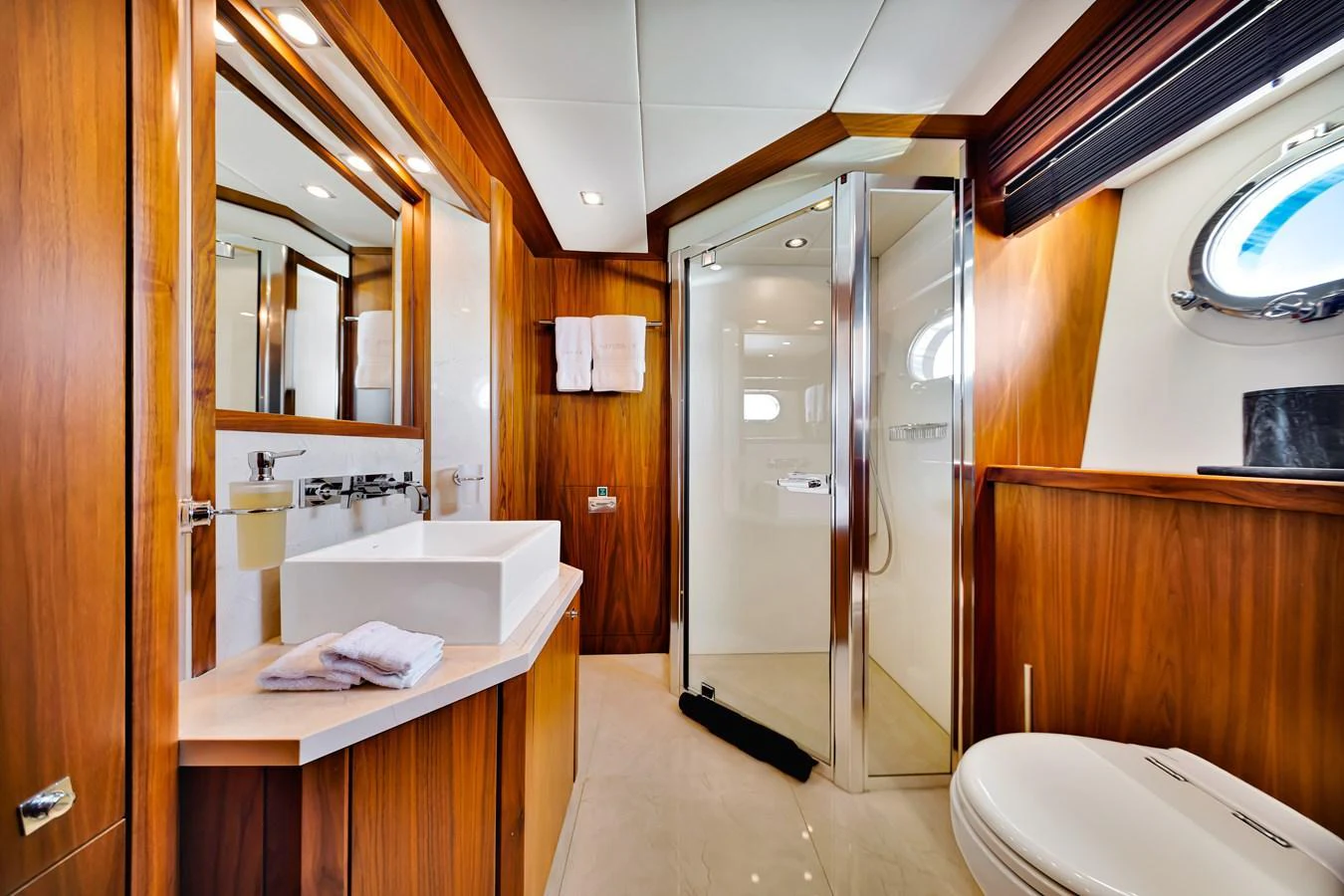The yacht's bathroom features elegant wood paneling, a modern sink, and a spacious shower area. aboard NATURAL 9 Yacht for Sale