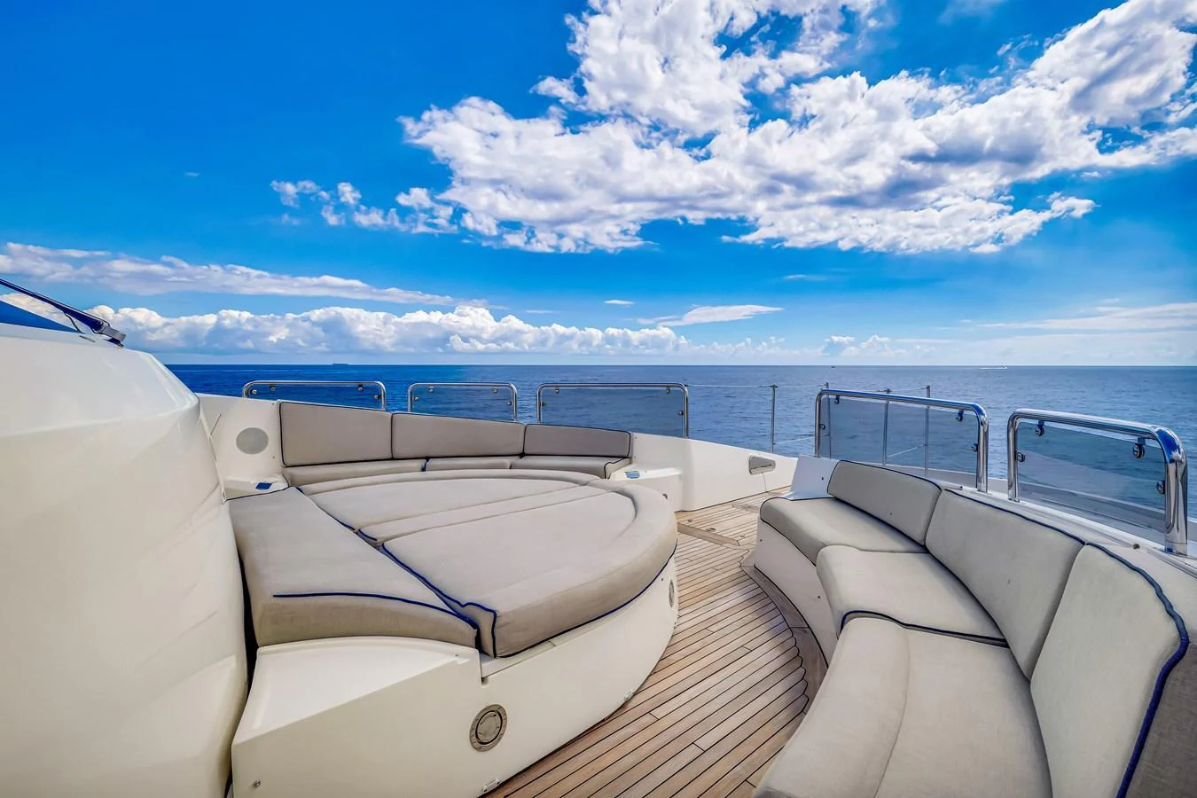 The flybridge offers a spacious seating area with panoramic ocean views under a clear blue sky. aboard NATURAL 9 Yacht for Sale