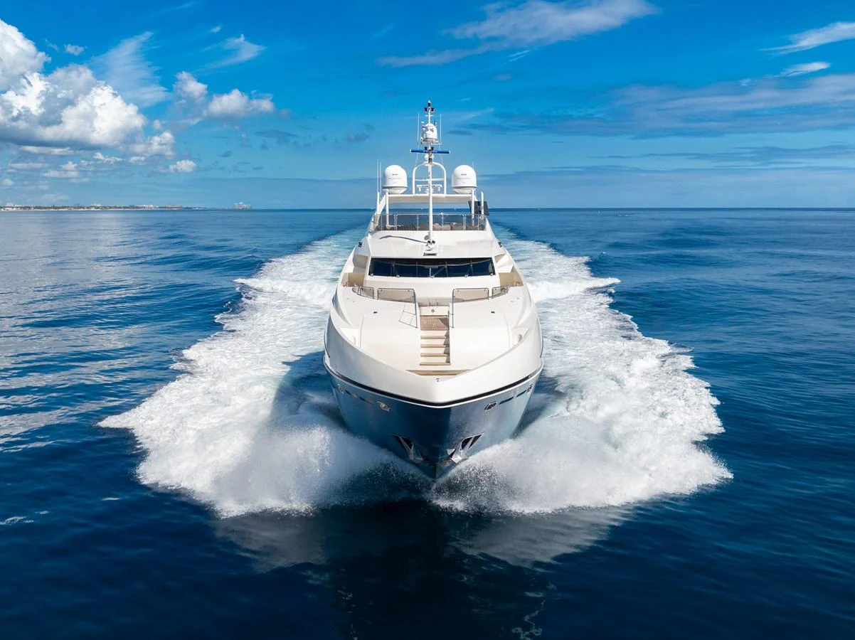 A sleek yacht cruises powerfully through calm blue waters under a clear sky. aboard NATURAL 9 Yacht for Sale