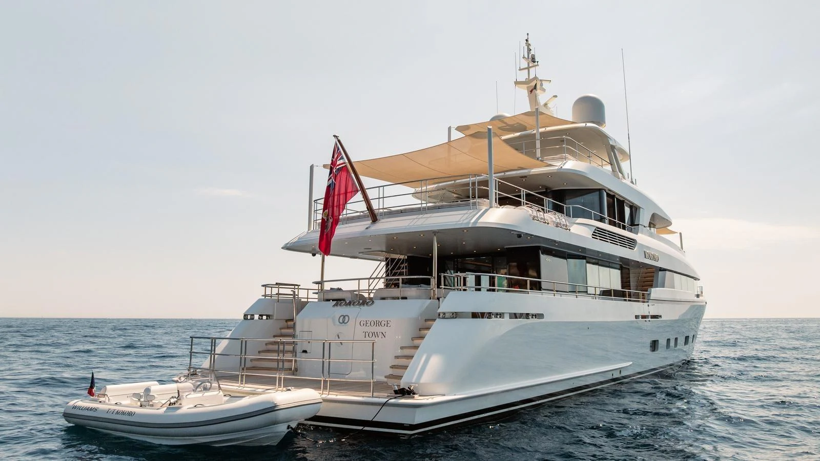 A luxurious yacht anchored at sea with a tender boat nearby. aboard KOKORO Yacht for Sale