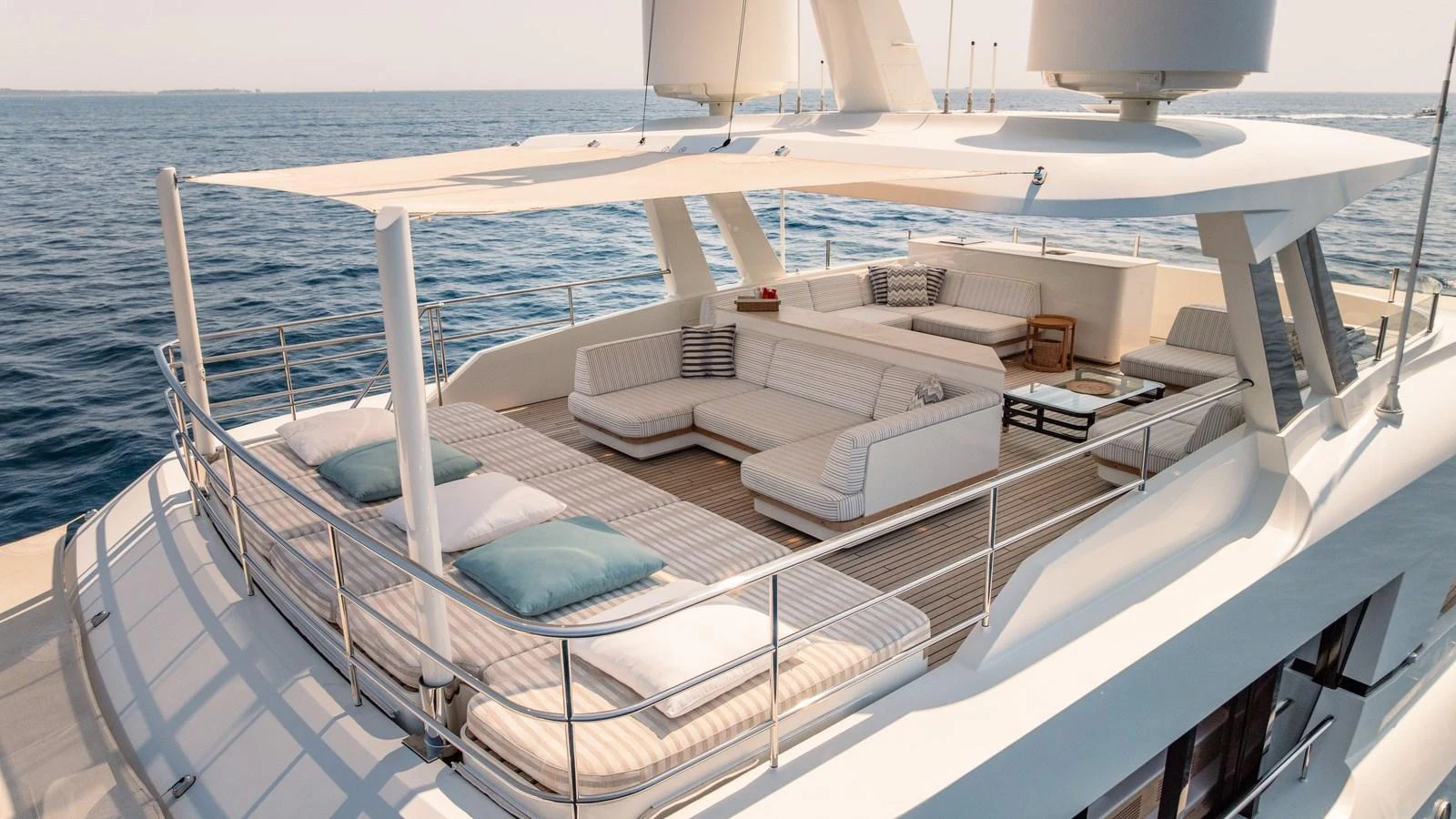 The flybridge offers a spacious and luxurious lounging area with plush seating and sunbeds under a sleek canopy. aboard KOKORO Yacht for Sale