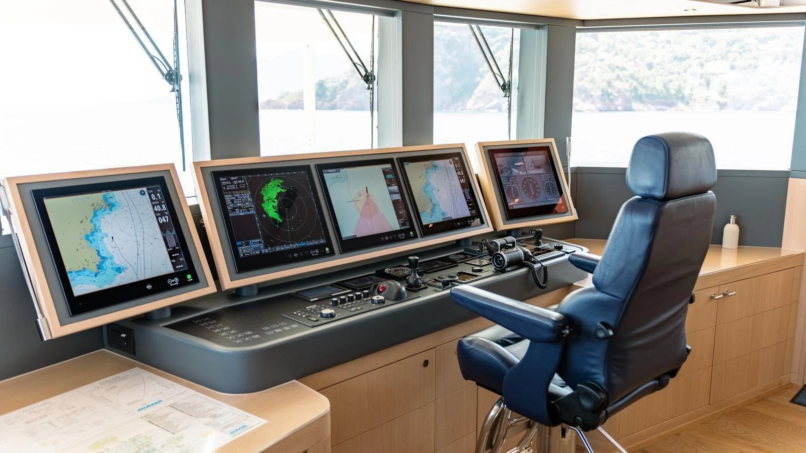 The helm station features advanced navigation equipment and a comfortable captain's chair with a scenic view. aboard KOKORO Yacht for Sale