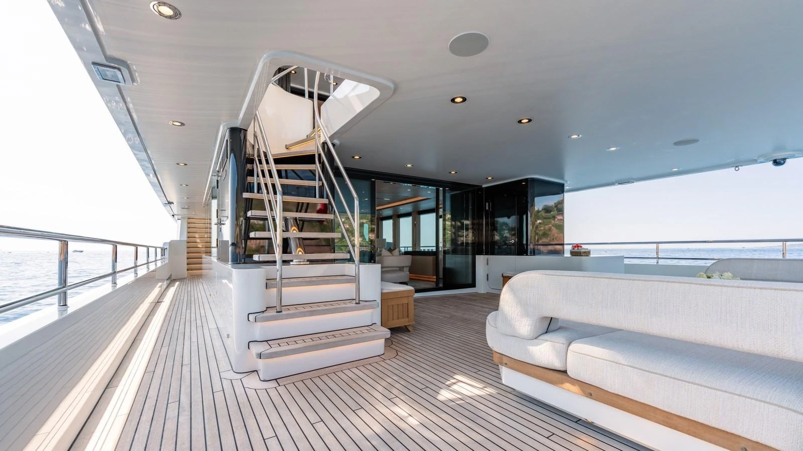 The aft deck features a spacious seating area with elegant furnishings and a staircase leading to the upper deck. aboard KOKORO Yacht for Sale