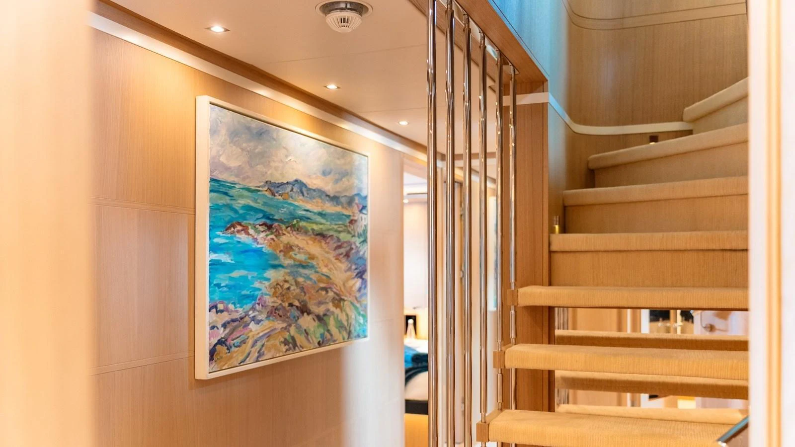 A beautifully lit staircase with a vibrant painting on the wall enhances the yacht's interior elegance. aboard KOKORO Yacht for Sale
