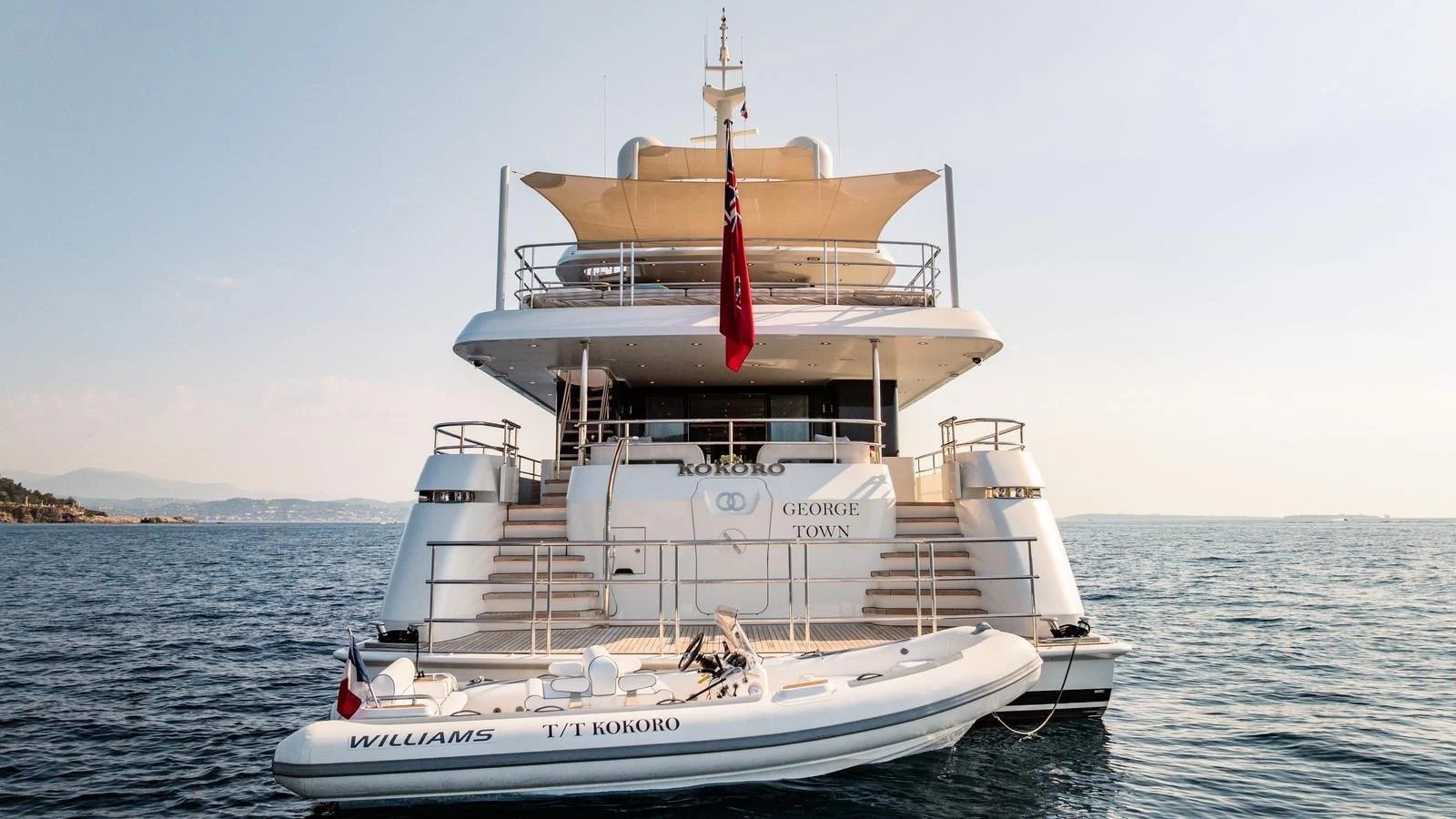 A luxurious yacht anchored on calm waters with a tender boat at the stern. aboard KOKORO Yacht for Sale