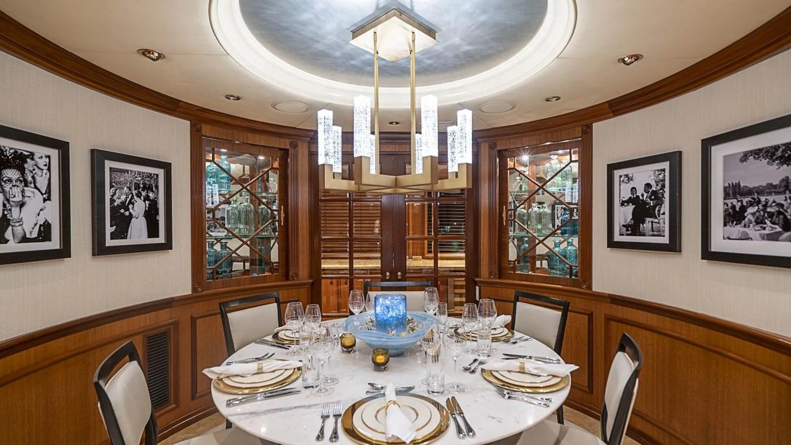 The yacht's dining area features an elegant round table set for a formal meal, surrounded by luxurious decor and ambient lighting. aboard TRUE NORTH Yacht for Sale