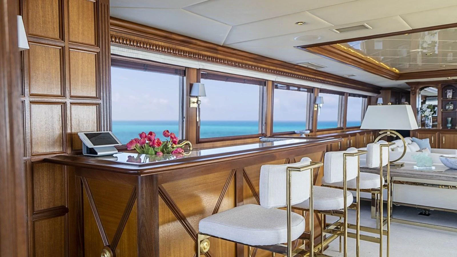 The yacht's salon features elegant wood paneling, a bar area, and large windows offering stunning ocean views. aboard TRUE NORTH Yacht for Sale