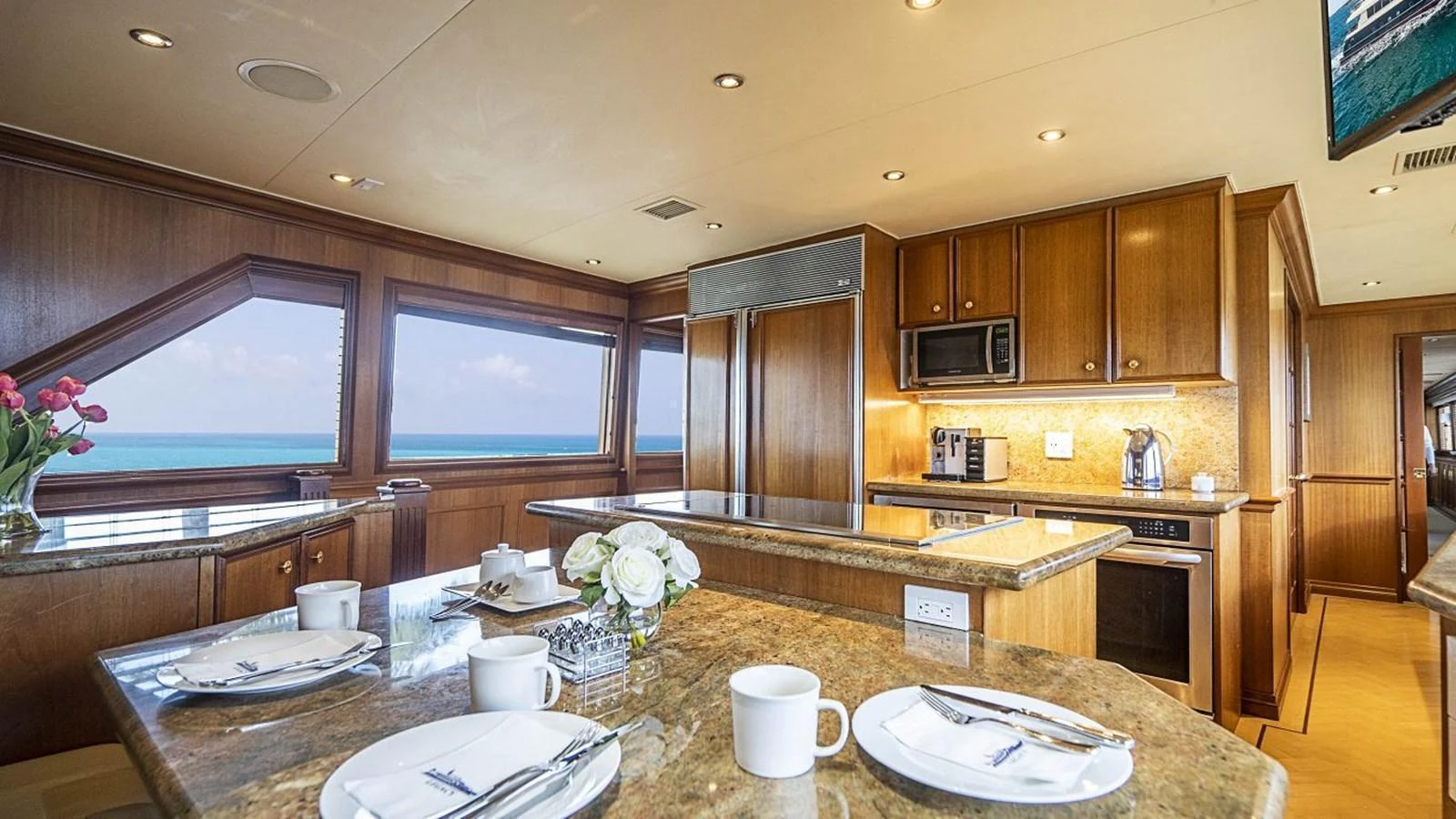 The galley features elegant wood cabinetry, modern appliances, and a spacious dining area with ocean views. aboard TRUE NORTH Yacht for Sale