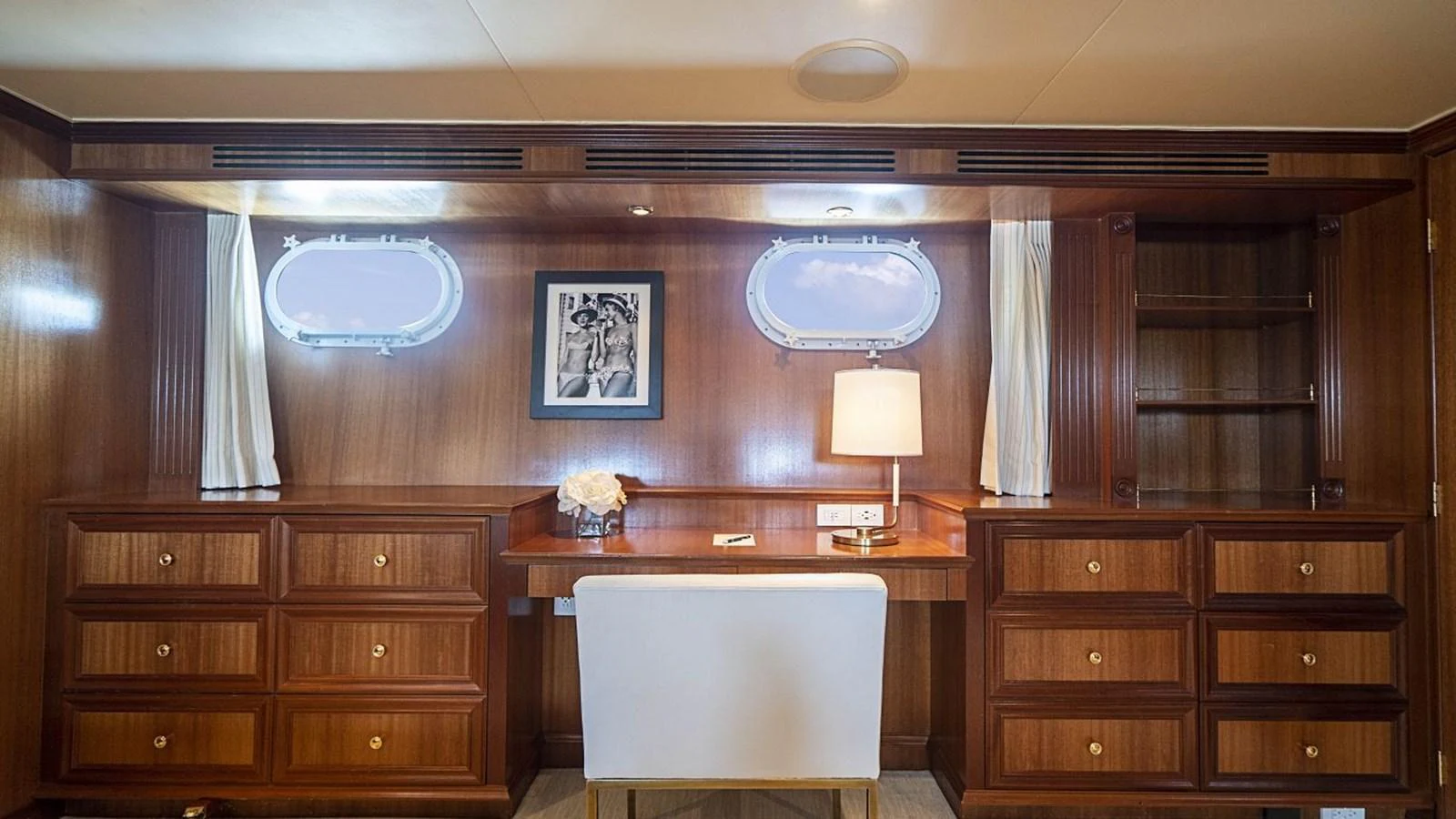 The yacht's office features elegant wooden cabinetry, a comfortable chair, and ample natural light from two portholes. aboard TRUE NORTH Yacht for Sale