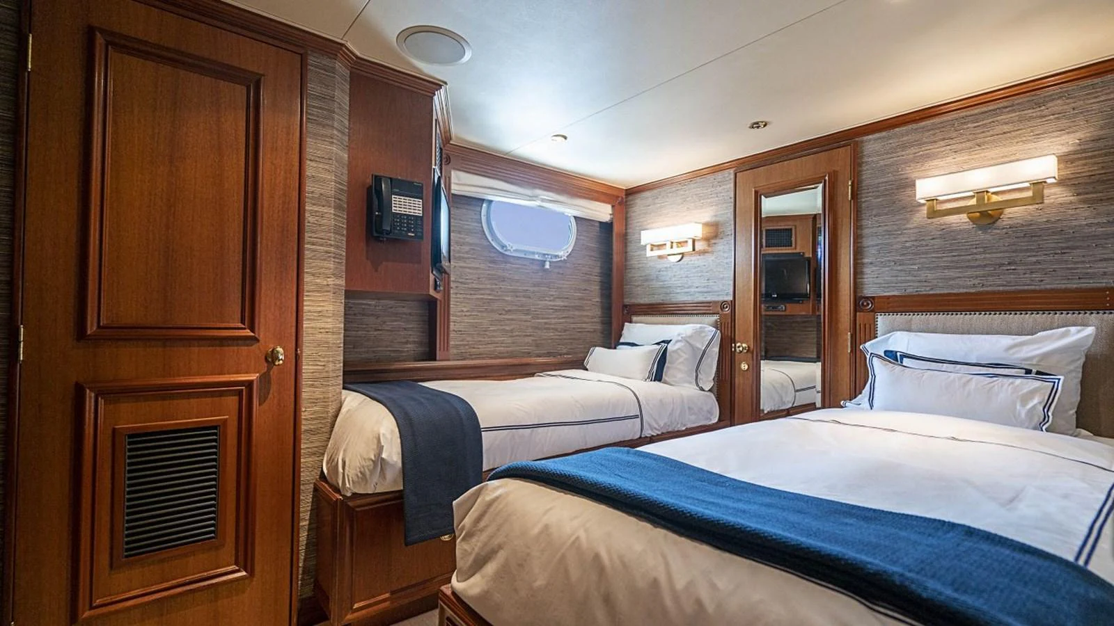 The guest stateroom features twin beds with elegant bedding and warm wood finishes. aboard TRUE NORTH Yacht for Sale