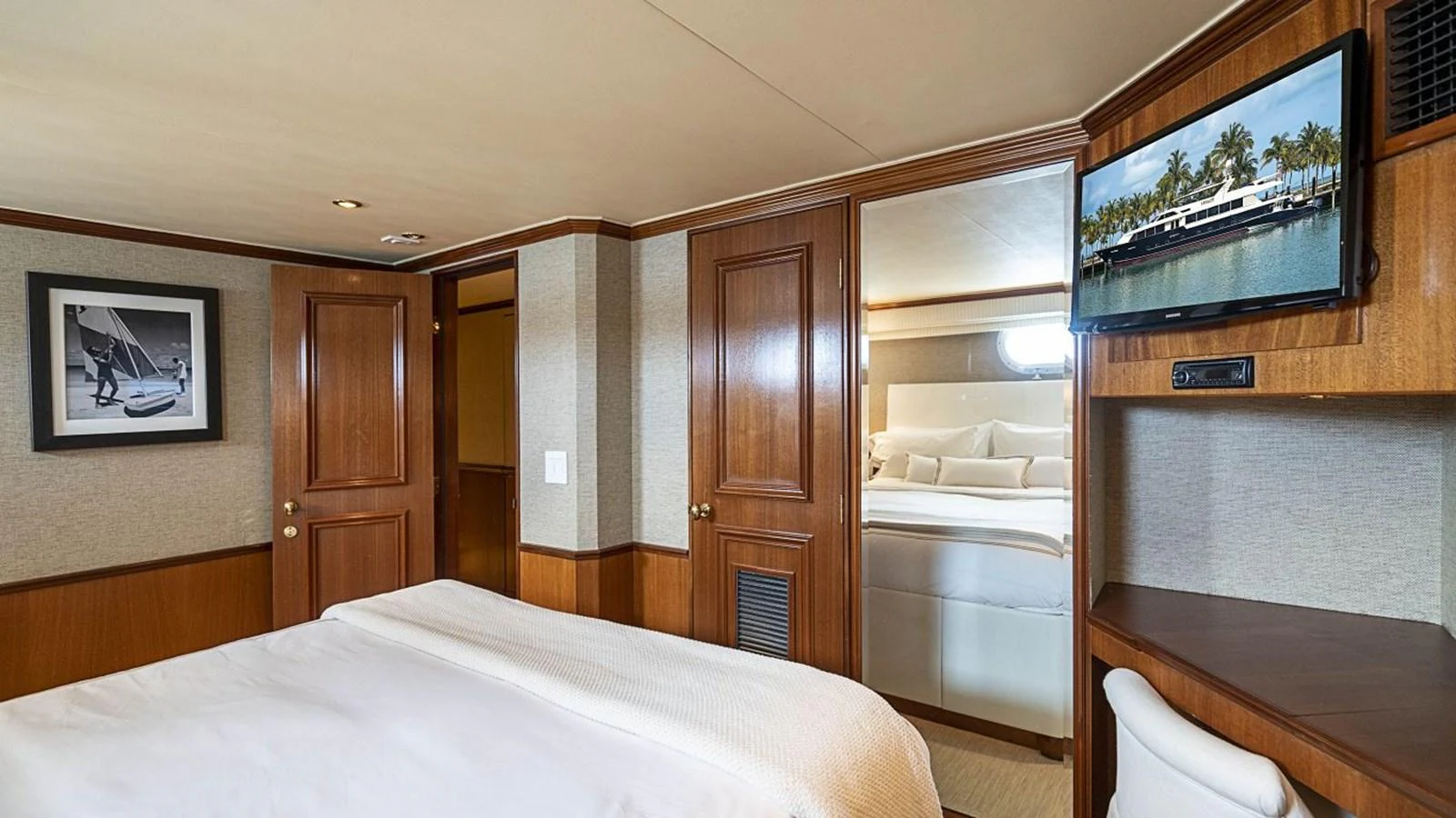 The stateroom features elegant wood paneling, a comfortable bed, and a television for entertainment. aboard TRUE NORTH Yacht for Sale