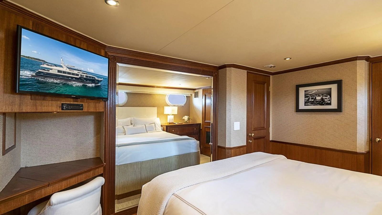 A luxurious stateroom featuring a comfortable bed, a wall-mounted TV, and elegant wood paneling. aboard TRUE NORTH Yacht for Sale
