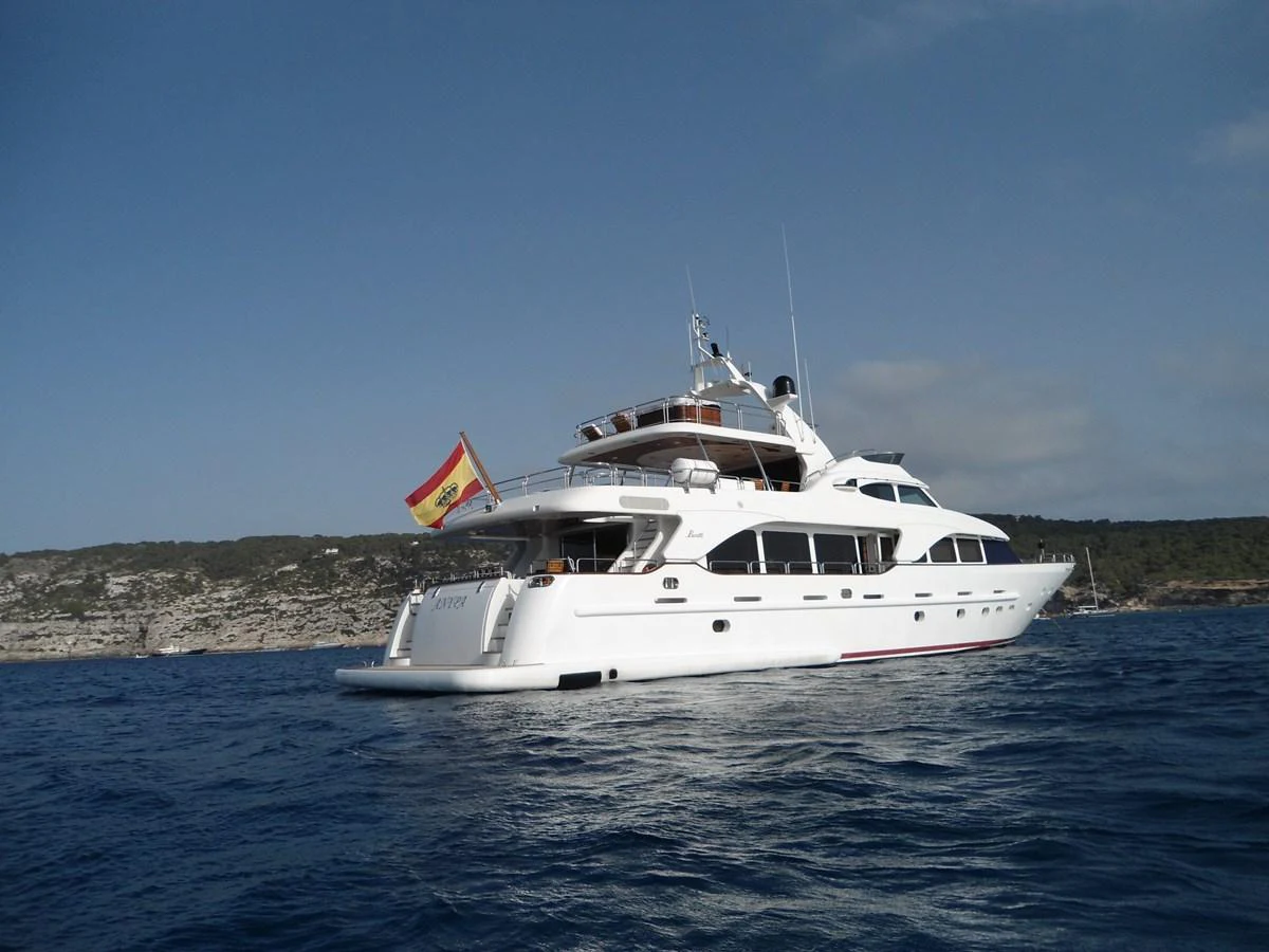 A luxurious white yacht cruises on calm blue waters with a scenic coastline in the background. aboard ANYPA Yacht for Sale