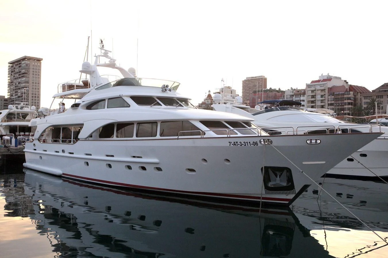 A sleek and elegant yacht is docked in a marina, showcasing its luxurious design against a backdrop of city buildings. aboard ANYPA Yacht for Sale
