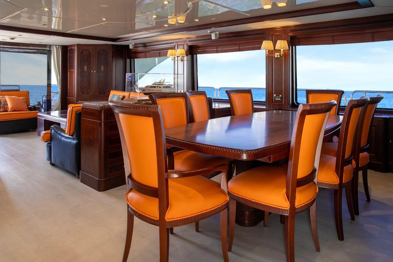 The yacht's dining area features elegant wooden furniture with vibrant orange upholstery, offering a luxurious setting for meals with a view of the sea. aboard ANYPA Yacht for Sale