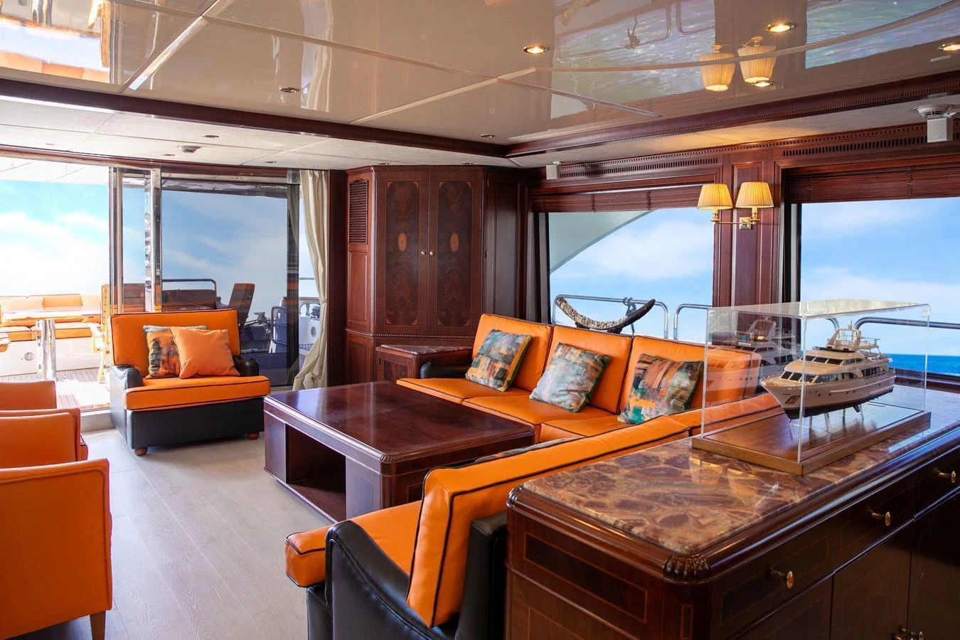 The salon features luxurious seating with vibrant orange accents and elegant wooden furnishings. aboard ANYPA Yacht for Sale