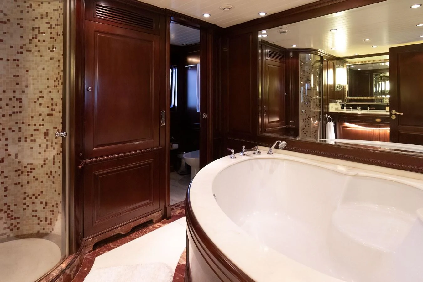 The luxurious bathroom features rich wood paneling, a spacious bathtub, and elegant fixtures. aboard ANYPA Yacht for Sale