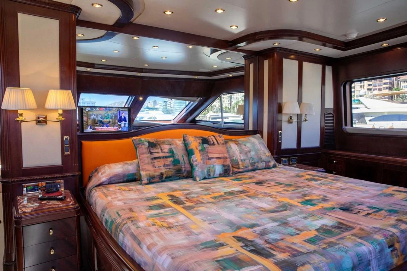 The master stateroom features a luxurious bed with vibrant bedding and ample natural light from large windows. aboard ANYPA Yacht for Sale
