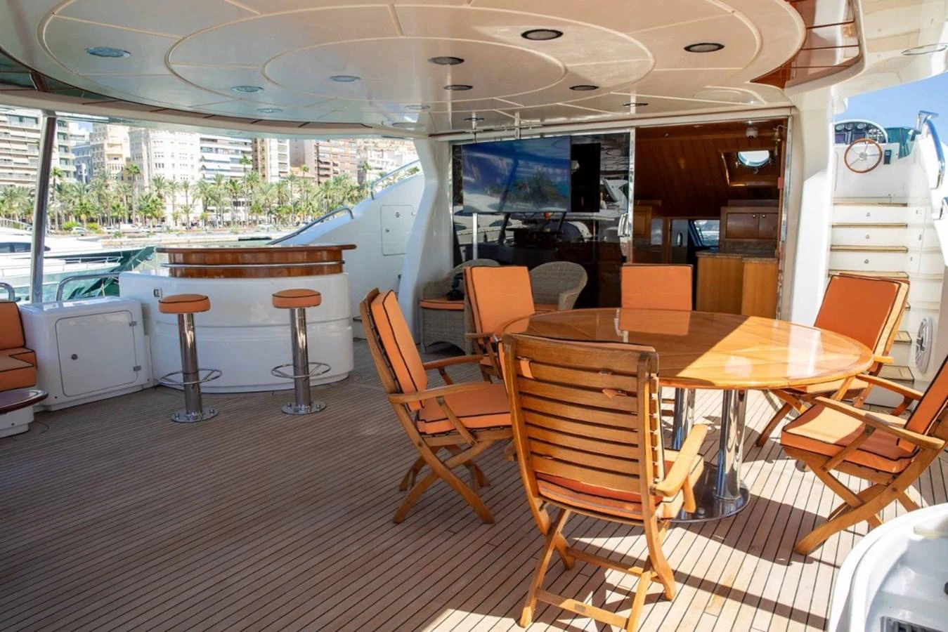 The aft deck features a spacious seating area with a wooden table and chairs, perfect for outdoor dining and relaxation. aboard ANYPA Yacht for Sale