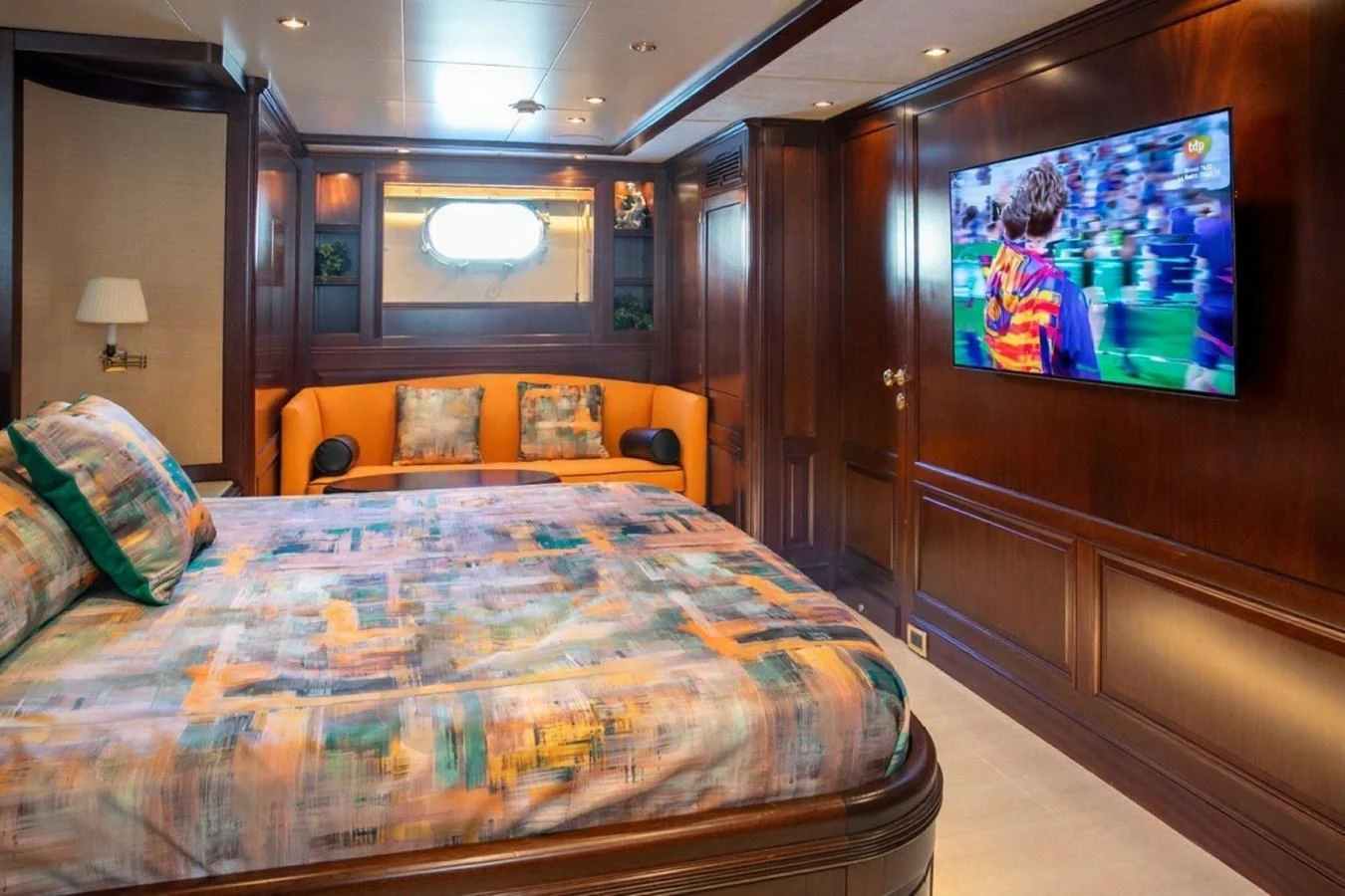 A luxurious stateroom featuring a large bed, a comfortable seating area, and a wall-mounted television. aboard ANYPA Yacht for Sale