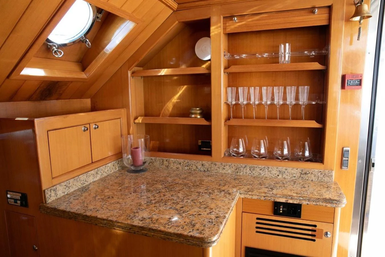 The yacht's galley features a granite countertop and wooden cabinetry with glassware neatly arranged on shelves. aboard ANYPA Yacht for Sale