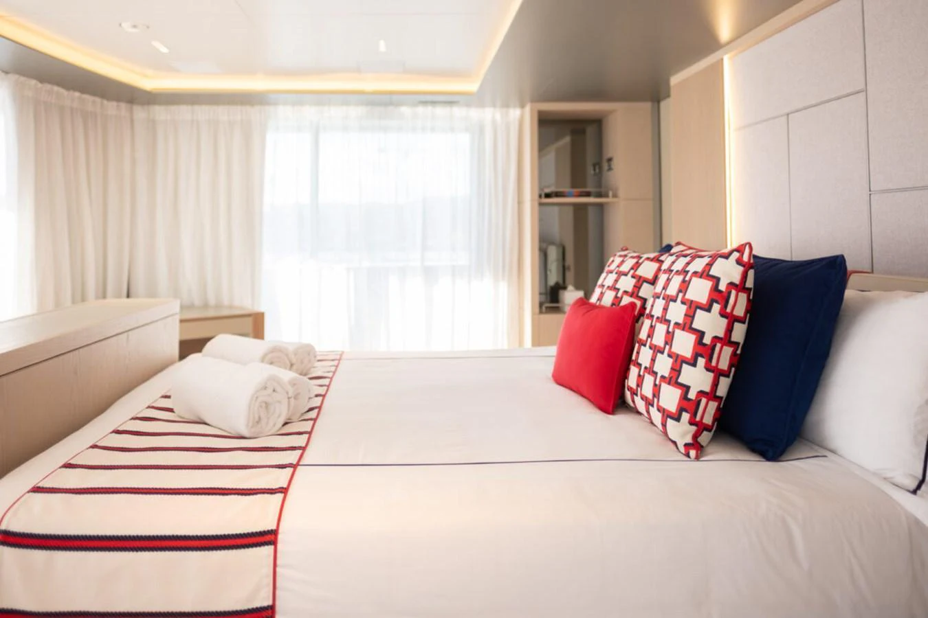 A luxurious stateroom featuring a neatly made bed with stylish pillows and soft lighting. aboard TOLEMAI Yacht for Sale
