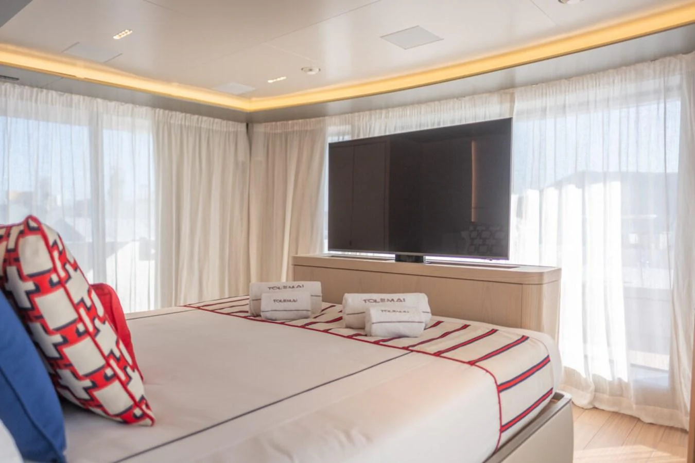 The stateroom features a large bed with decorative pillows and a flat-screen TV, creating a cozy and luxurious atmosphere. aboard TOLEMAI Yacht for Sale