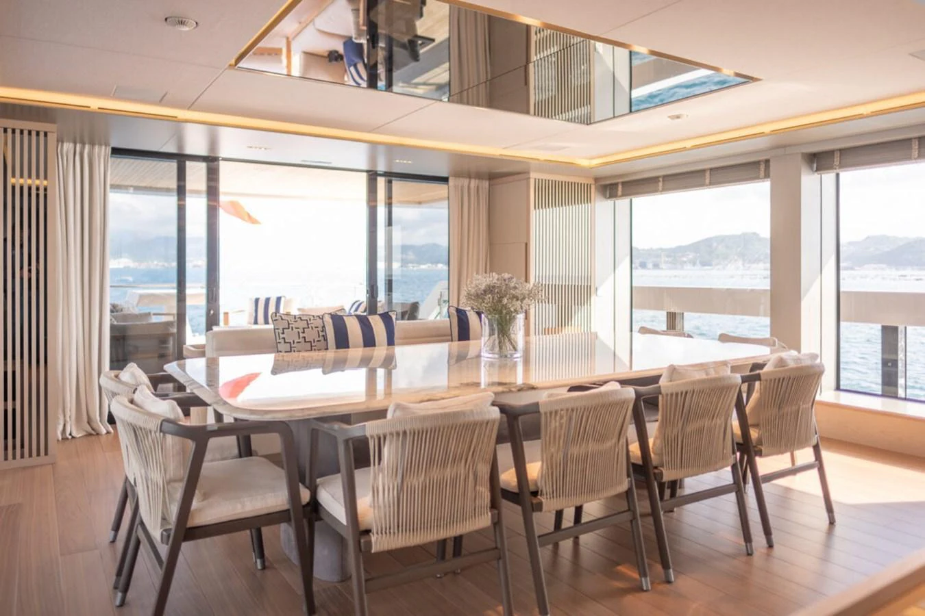 The yacht's dining area features a large table with ample seating and panoramic windows offering stunning sea views. aboard TOLEMAI Yacht for Sale