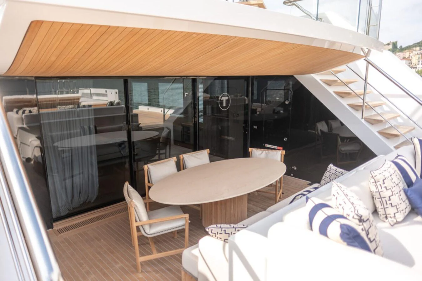 The aft deck features a stylish outdoor dining area with comfortable seating and a sleek wooden ceiling. aboard TOLEMAI Yacht for Sale