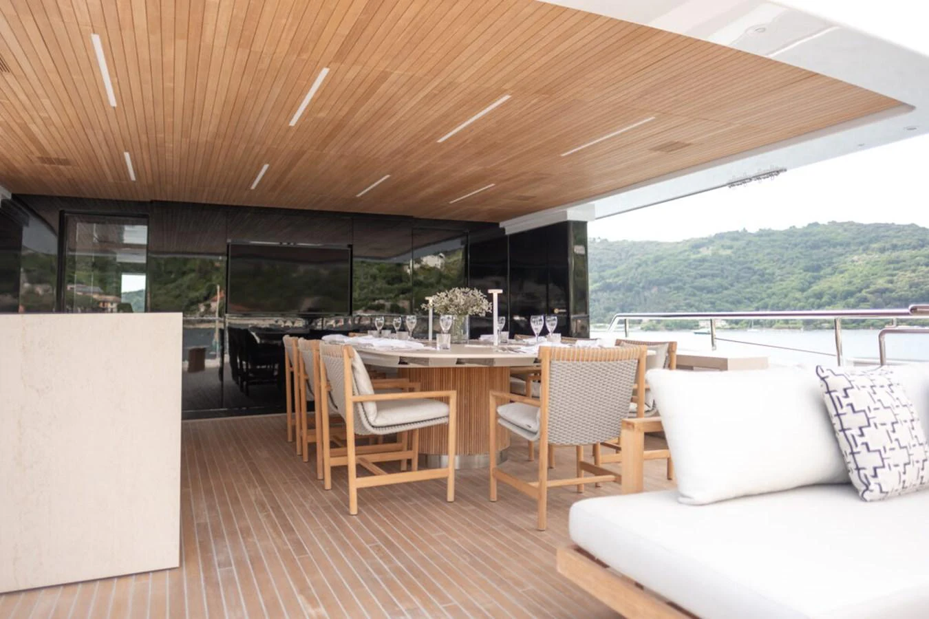 The aft deck features a stylish dining area with comfortable seating and a scenic view. aboard TOLEMAI Yacht for Sale