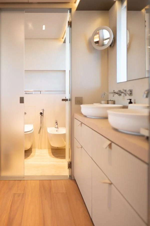 The yacht's bathroom features a modern design with dual sinks and a separate toilet area. aboard TOLEMAI Yacht for Sale