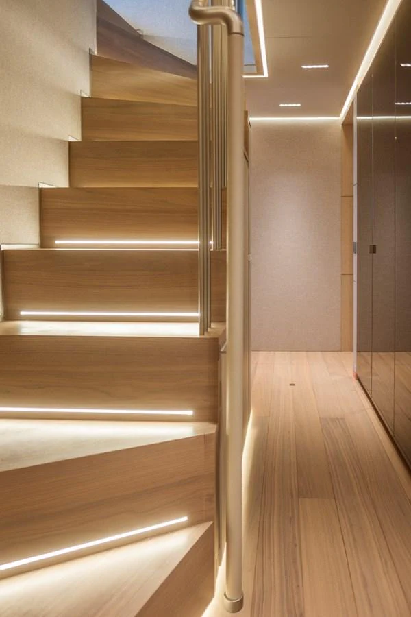 A beautifully illuminated wooden staircase leads to the upper deck of the yacht. aboard TOLEMAI Yacht for Sale